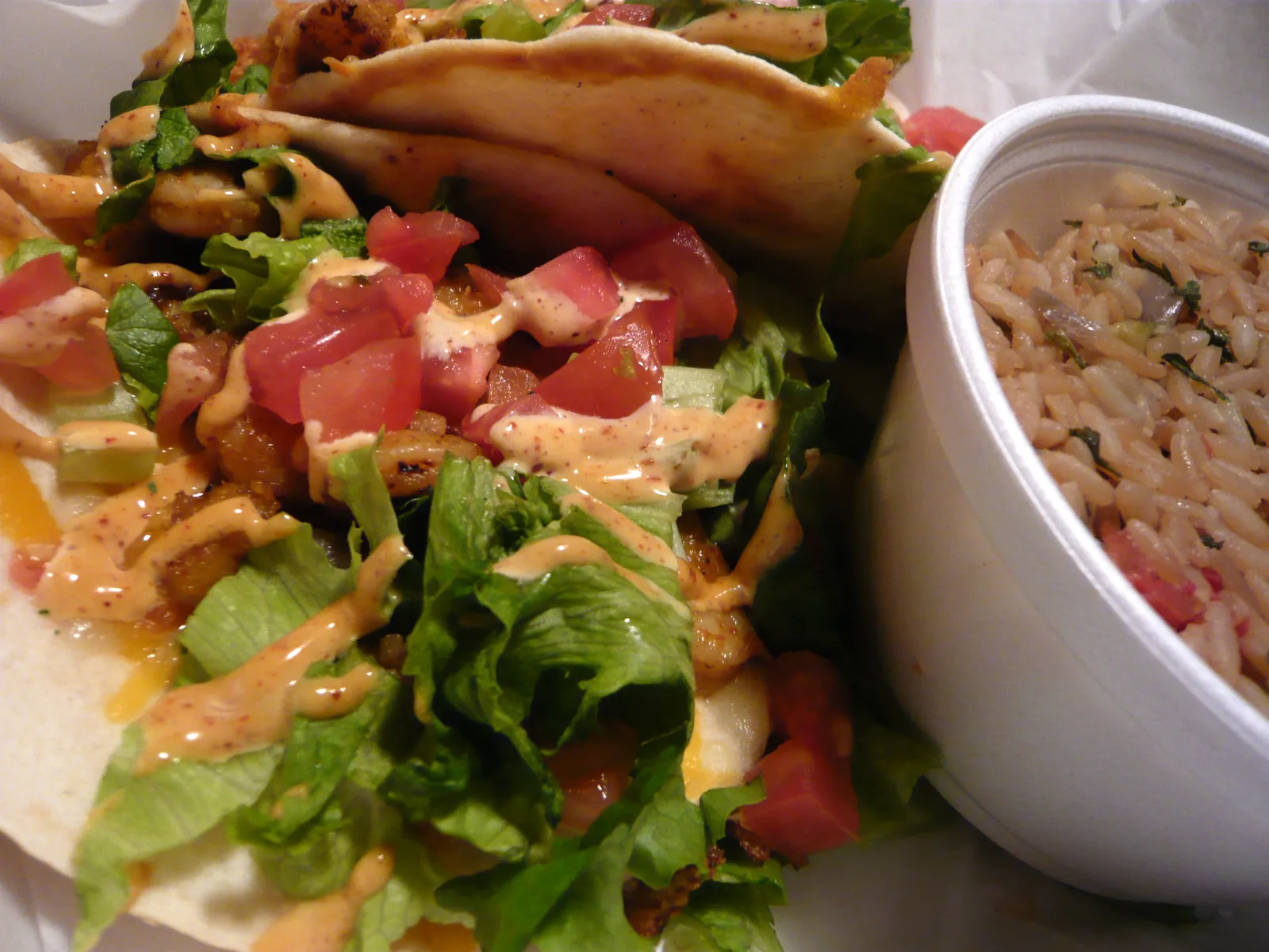 Shrimp tacos with rice in a takeout container, served at a restaurant that is not on this list.